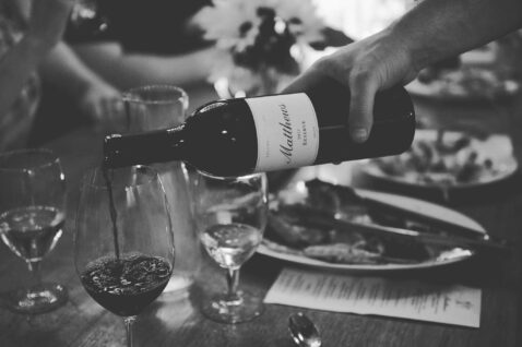 A bottle of 2013 Claret being poured into a glass on a dinner table