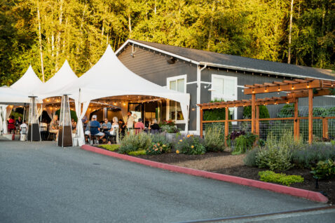 View of the white tents in front of the Matthews tasting room with customers seating at tables tasting