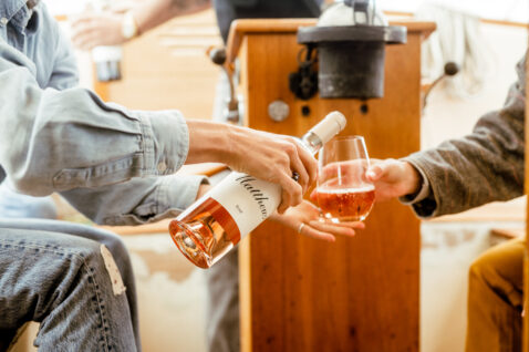 Closeup of a bottle of Rose being poured into a stemless wine glass in the galley of a sailboat