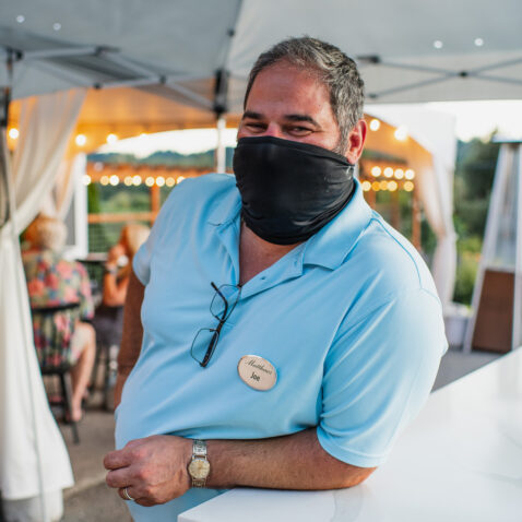 Matthews employee smiling under mask leaning on counter