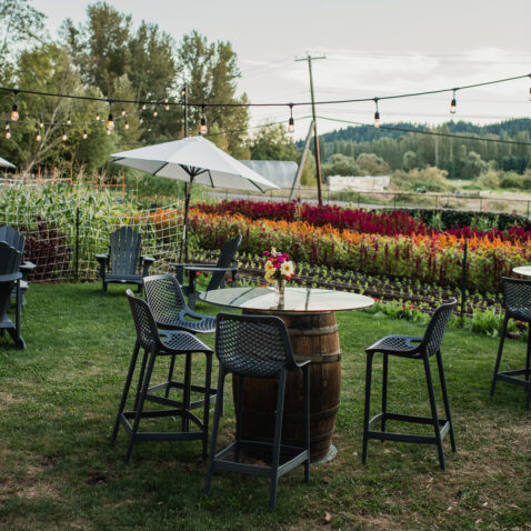 Barrel table and chairs placed in the farm seating area with farm rows in the background