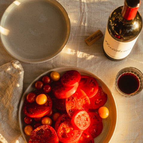 Looking down on a bowl of freshly cut heirloom tomatoes and a bottle of Reserve Cabernet Franc