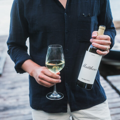 Man in navy shirt holding bottle of 2019 Reserve Sauv Blanc and full glass