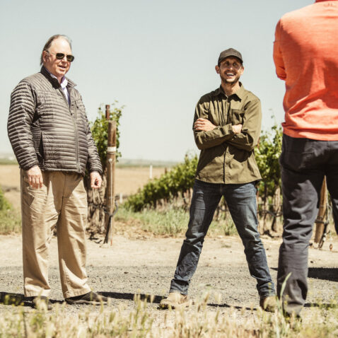 Owner Cliff Otis, vineyard manager and others talking in a circle in the vineyards