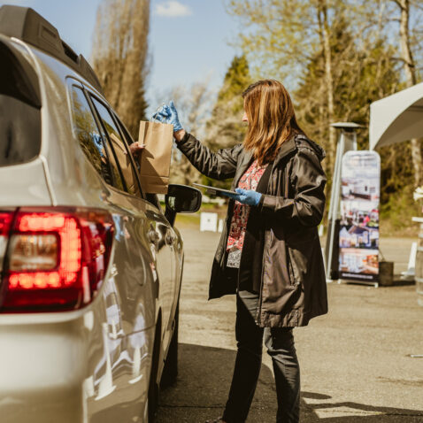 Matthews employee handing a wine bag to a customer in their car at curbside pick up