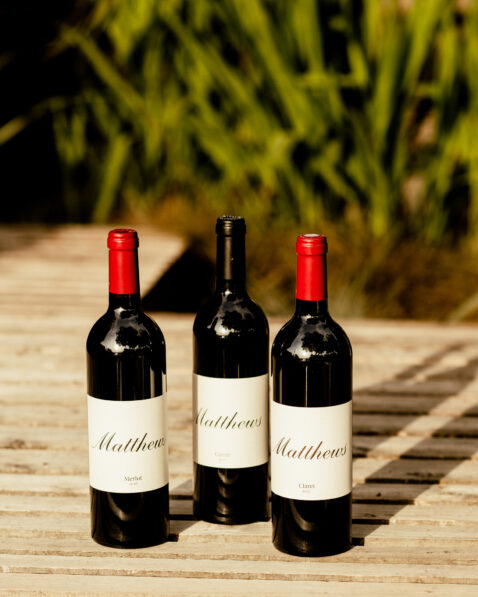 Bottles of Claret, Cuvee and Cab Sauv sitting on a bench