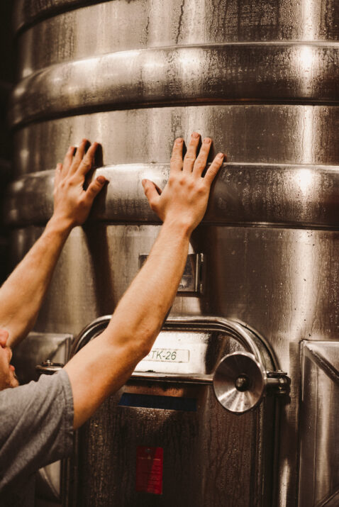 Male hands touching the outside of a cold stainless steel tank