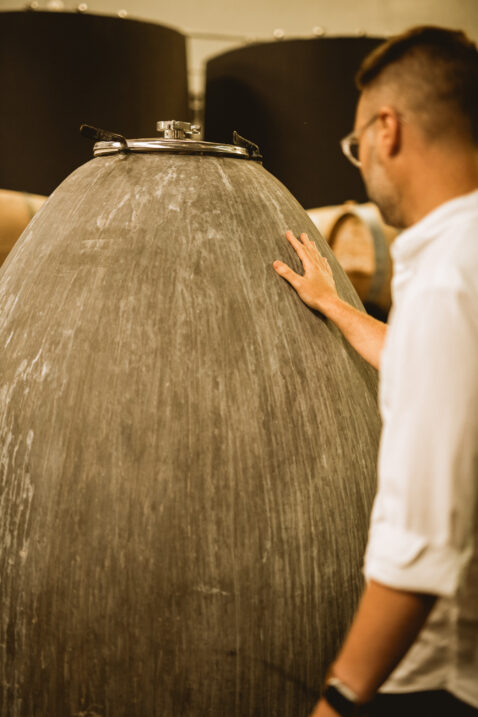 Owner Bryan Otis touching the outside of a concrete egg vessel