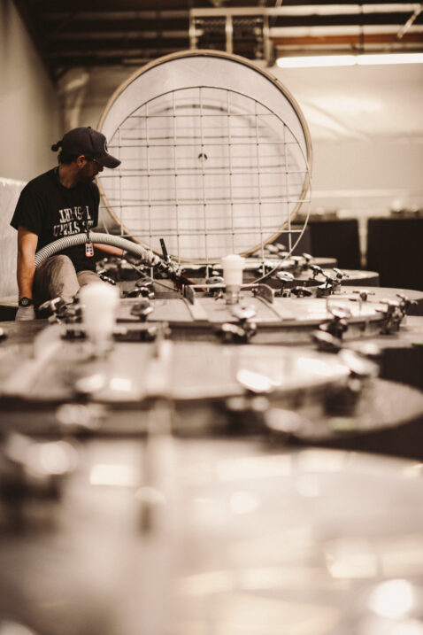 Looking down a row of cement tanks with an employee filling the farthest thank with a large hose