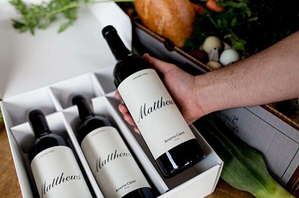 A 3 bottle box displaying the 2014 Reserve Claret, with a males hand lifting the far right bottle out of the box