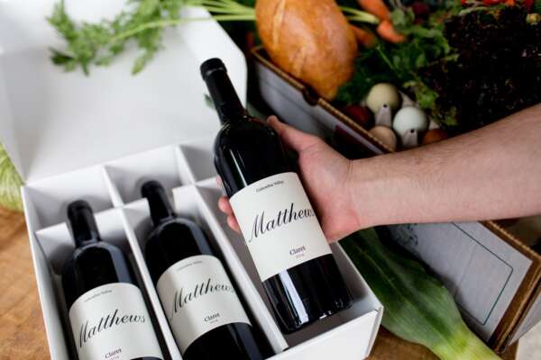 A 3 pack of Claret bottles with a males hand lifting the far right bottle out of the box