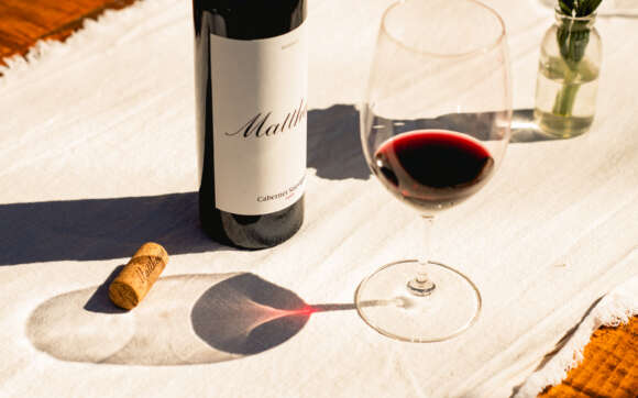 Close up of 2016 Matthews Reserve Cab Sauv on table with cork and wine glass next to it