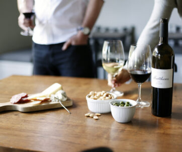 A wood table of red and white wine glasses, charcuterie, almonds and olives