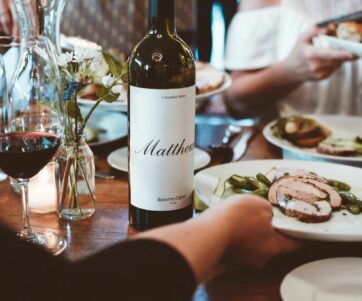 A bottle of the 2014 Reserve Claret in a dining table with plates of food being passed around it
