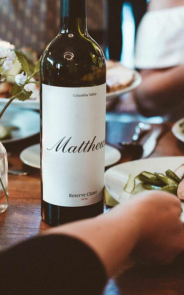 A bottle of the 2014 Reserve Claret in a dining table with plates of food being passed around it