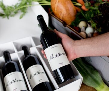 A 3 pack of Claret bottles with a males hand lifting the far right bottle out of the box